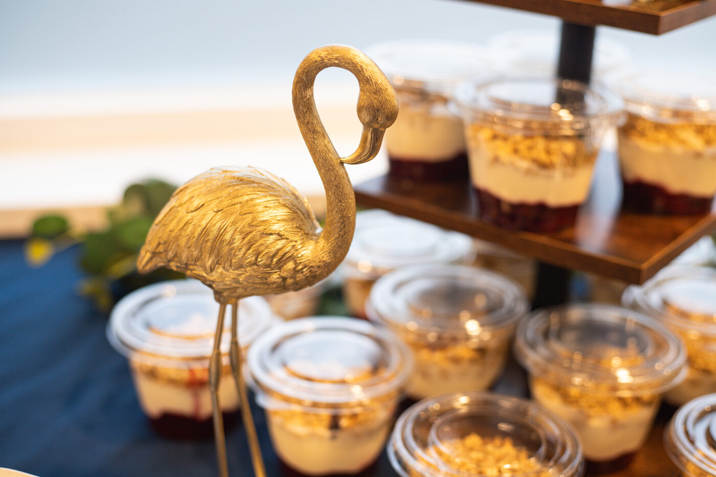 Tiered display of individual granola and yogurt pots styled with eucalyptus and a gold flamingo