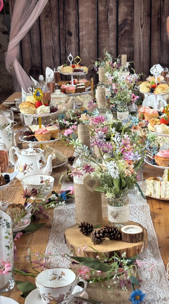 Rustic celebration table with tiered cake stands, cupcakes and wildflowers