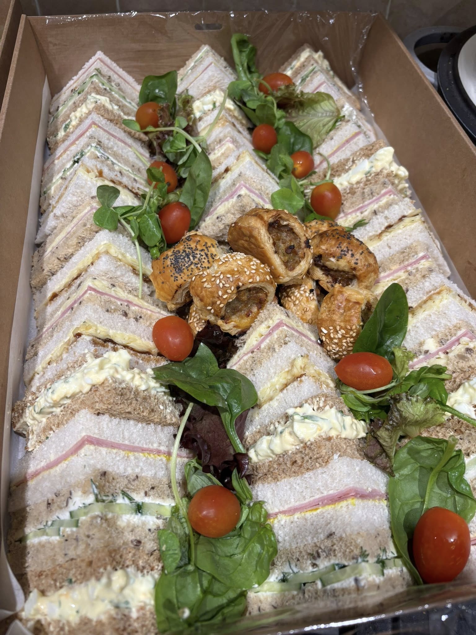 Assorted sandwich platter with sausage rolls and fresh garnish