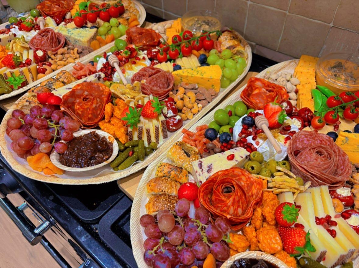 Long grazing board laden with cured meats, creamy cheeses and fresh berries
